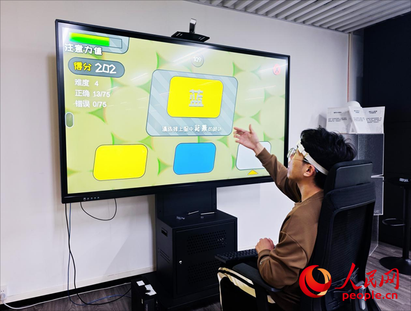 广州琶洲实验室工作人员演示脑机接口设备如何操作专注力训练游戏。人民网朴馨语摄